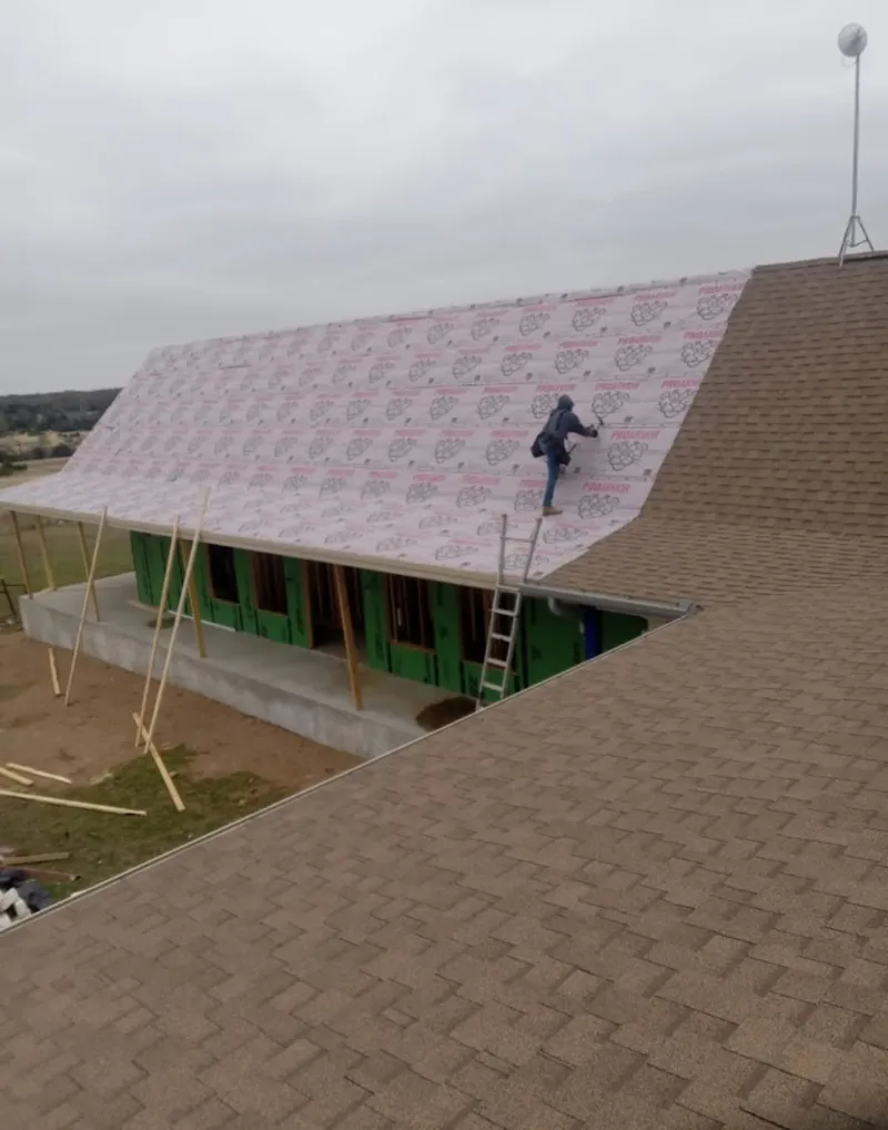 Worker preparing underlayment for a metal roof installation in Zebulon